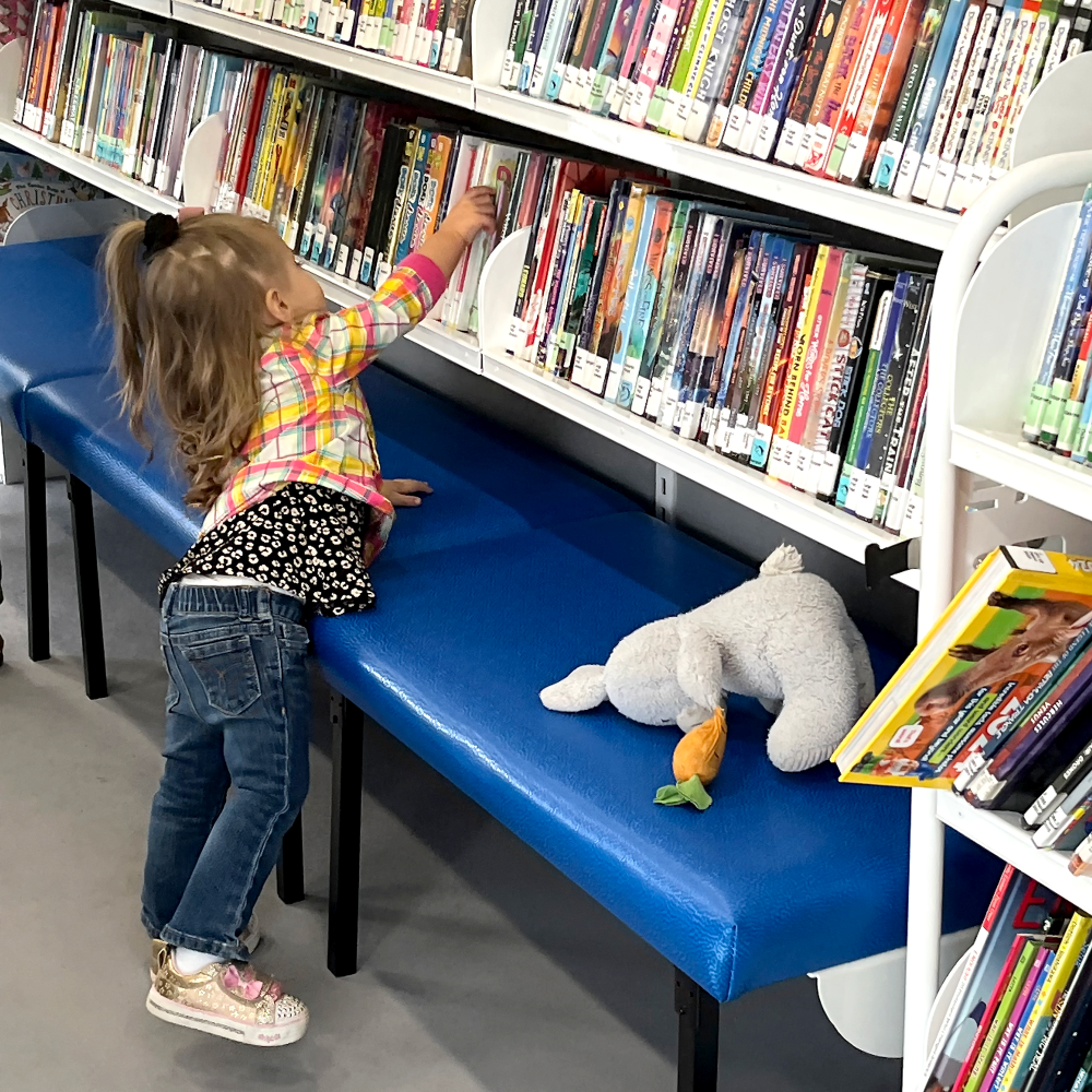 Little girl reaching for a book